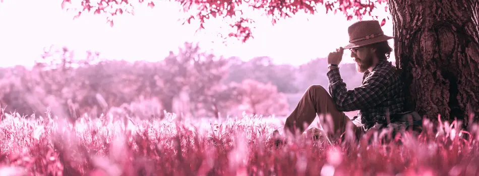 Mann lehnt an einem Baum und sieht nachdenklich aus