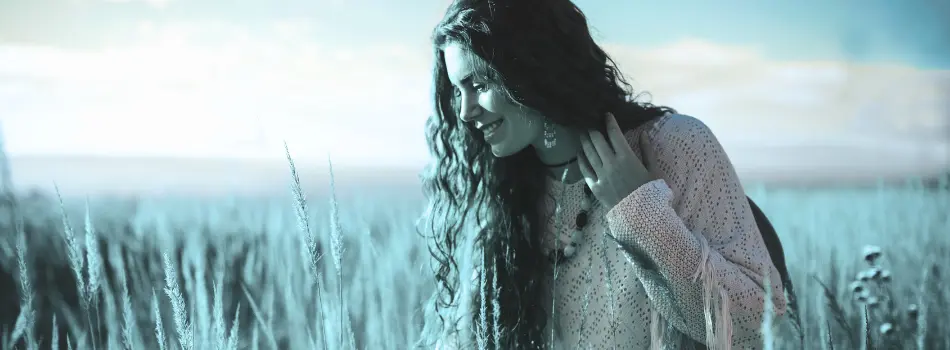 Frau steht glücklich länchend in einem Kornfeld mit weitem Horizont